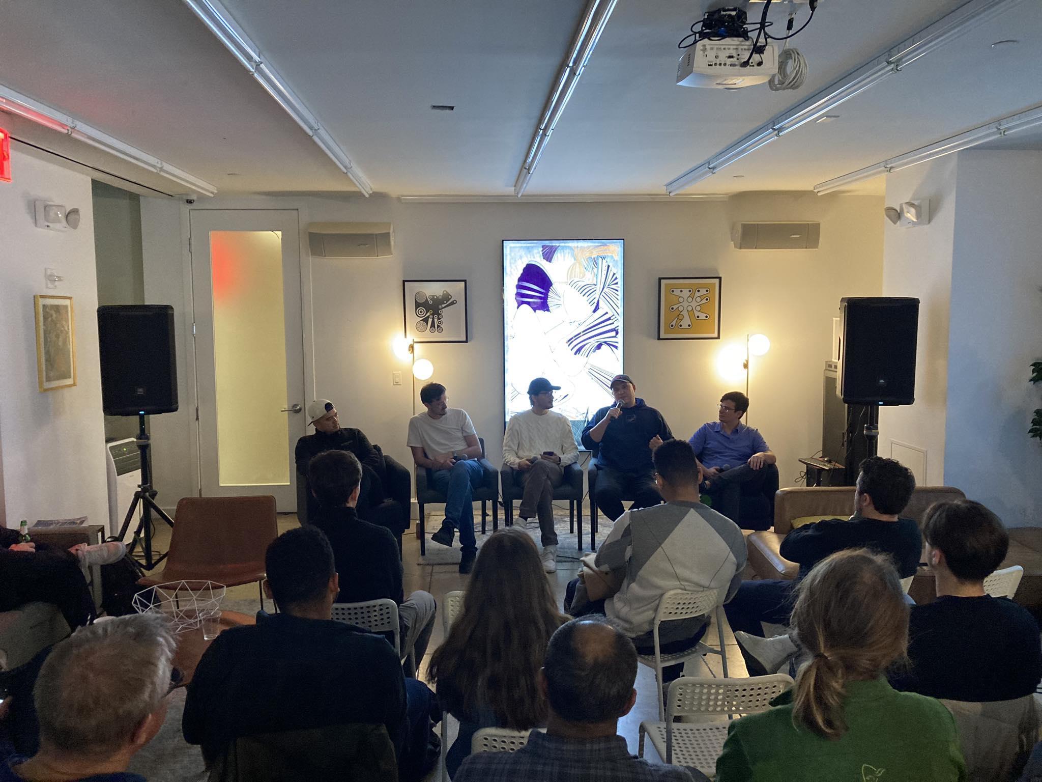 A picture of a five person panel speaking to many attendees